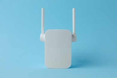 Photo of New modern Wi-Fi repeater on light blue background