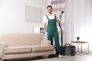 Photo of Professional janitor cleaning sofa in living room