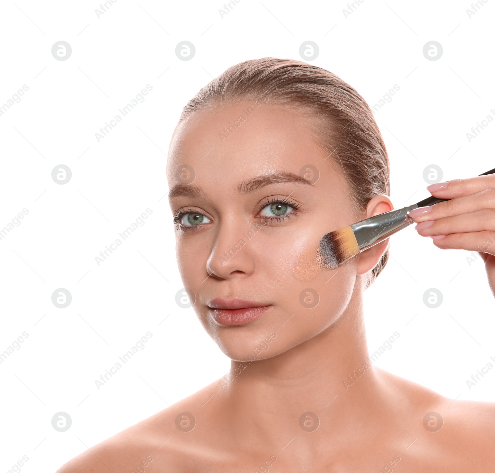 Photo of Young woman applying foundation on her face against white background