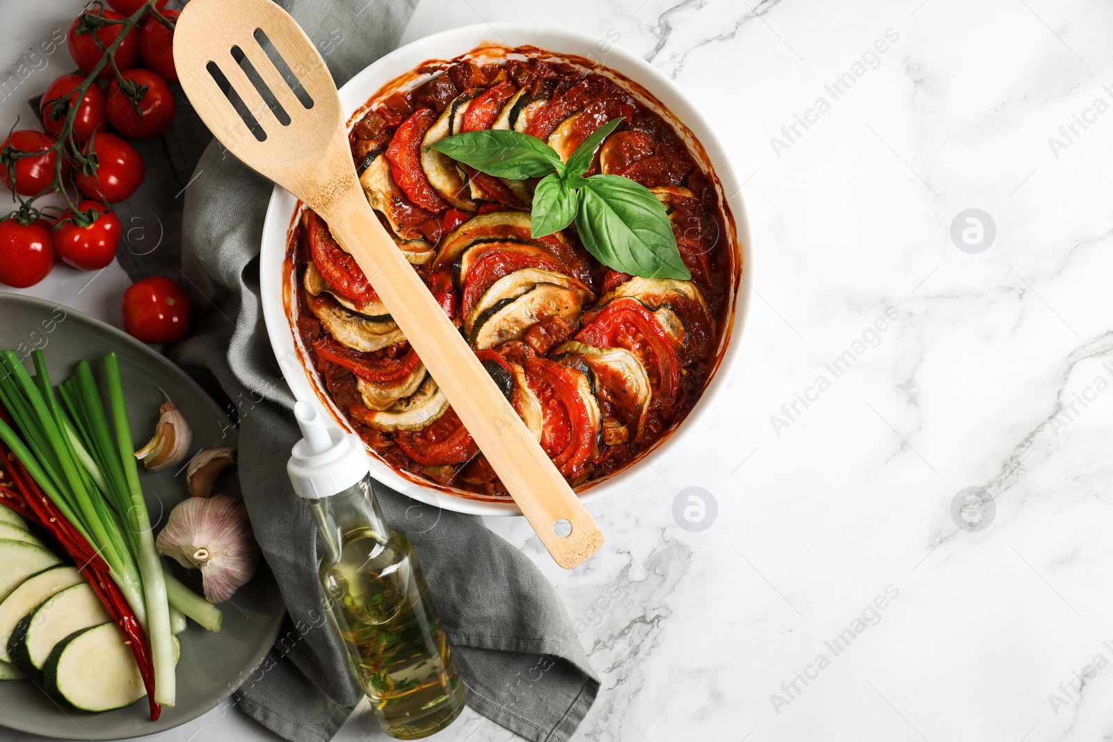 Photo of Delicious ratatouille and ingredients on white marble table, flat lay. Space for text