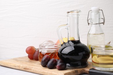 Photo of Different types of vinegar and grapes on table