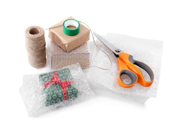 Photo of Cardboard boxes, bubble wrap, scissors and adhesive tape on white background