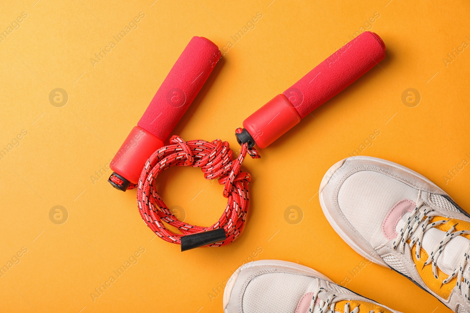 Photo of Jump rope and sneakers on color background. Healthy lifestyle