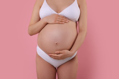 Pregnant woman in stylish comfortable underwear on pink background, closeup