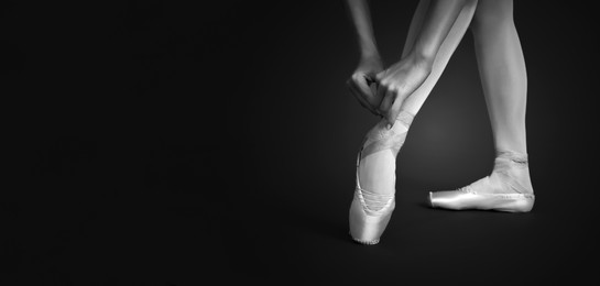 Image of Young ballerina tying pointe shoes, closeup. Black and white effect. Banner design with space for text