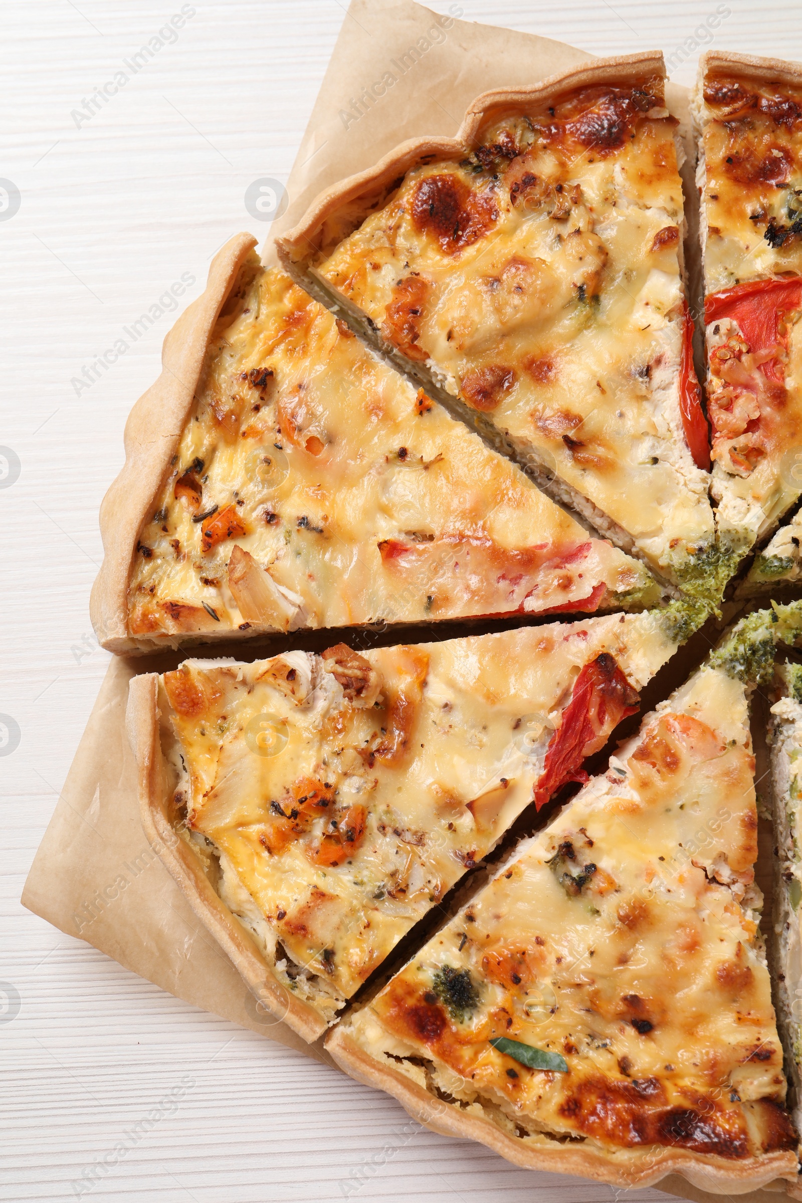 Photo of Tasty quiche with tomatoes and cheese on white wooden table, top view