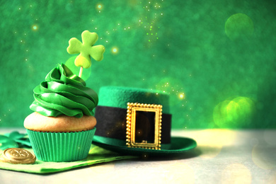 Decorated cupcake, hat and coin on grey table, space for text. St. Patrick's Day celebration