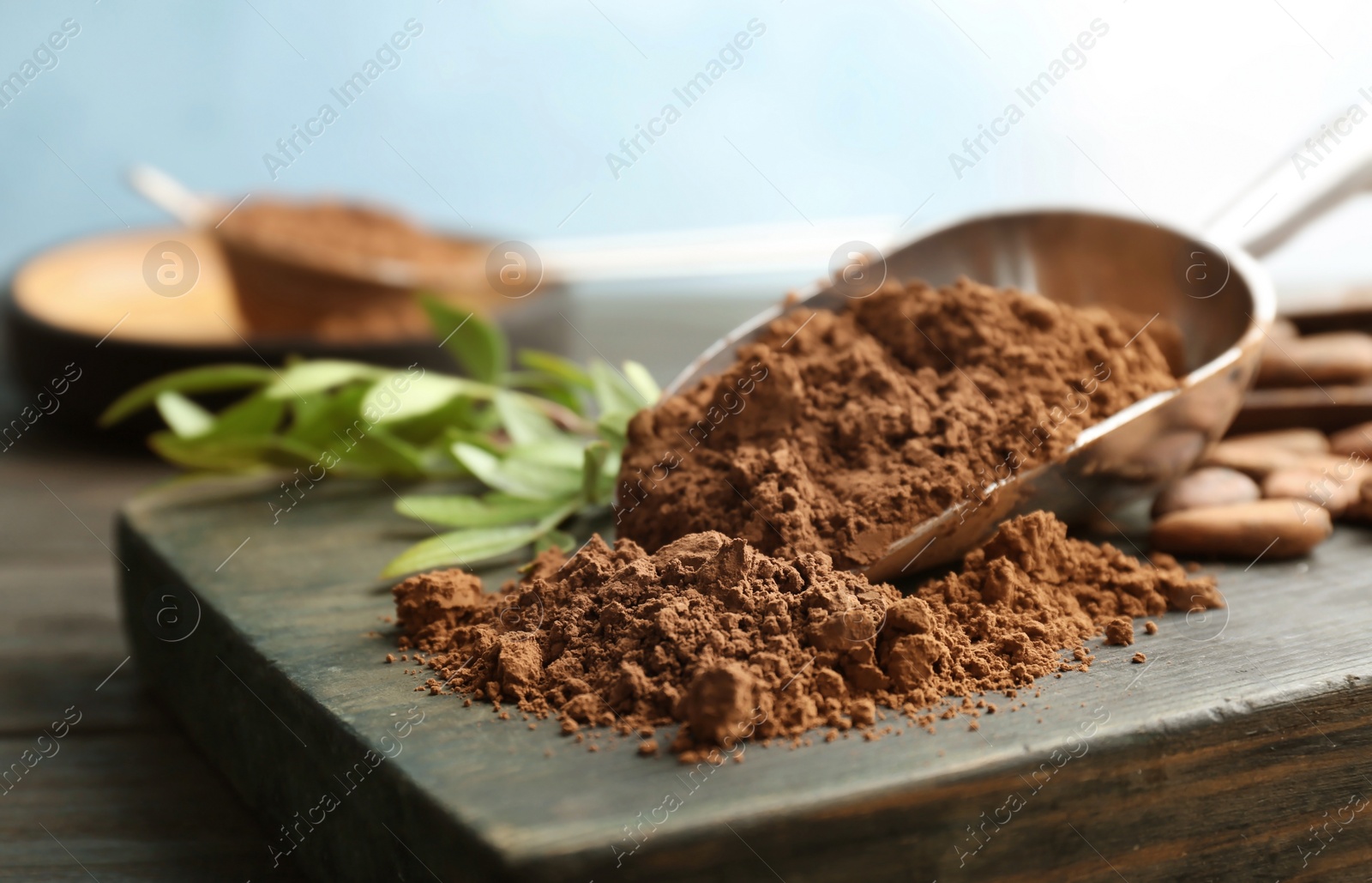 Photo of Scoop with cocoa powder on wooden board