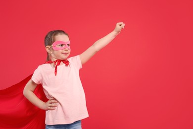 Photo of Little girl in superhero costume on red background. Space for text