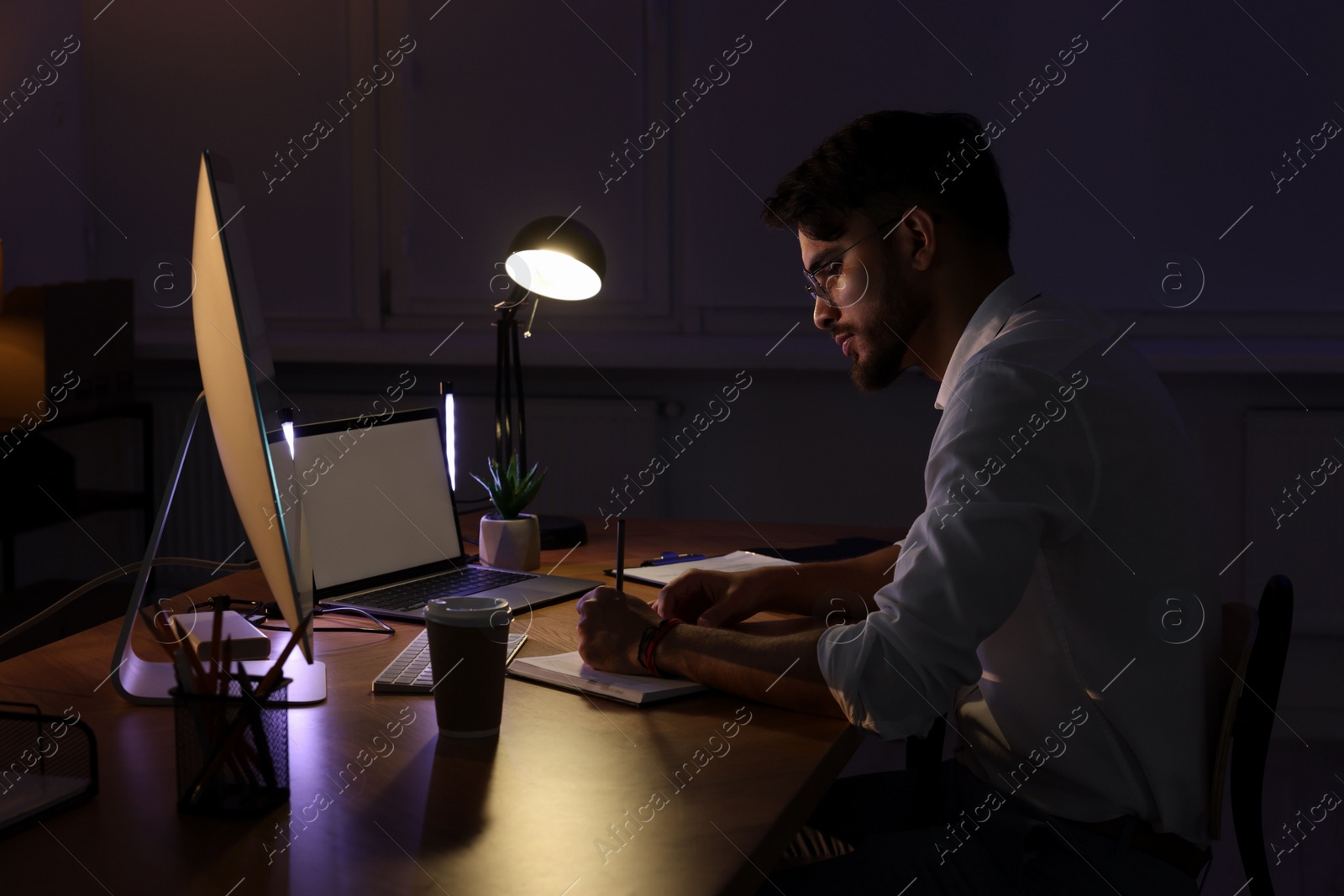 Photo of Tired young man working late in office