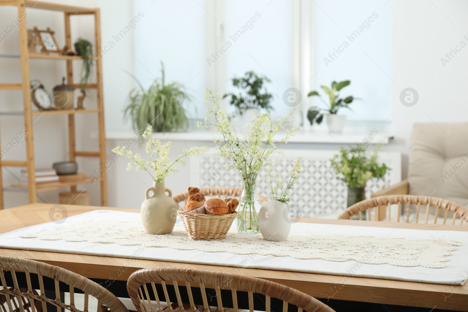 Photo of Fresh pastries and beautiful flowers on table in stylish dining room