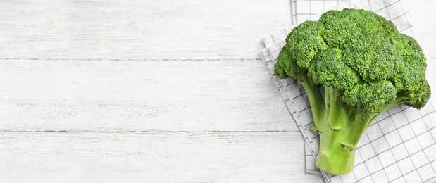 Image of Top view of fresh green broccoli on white wooden table, space for text. Banner design 