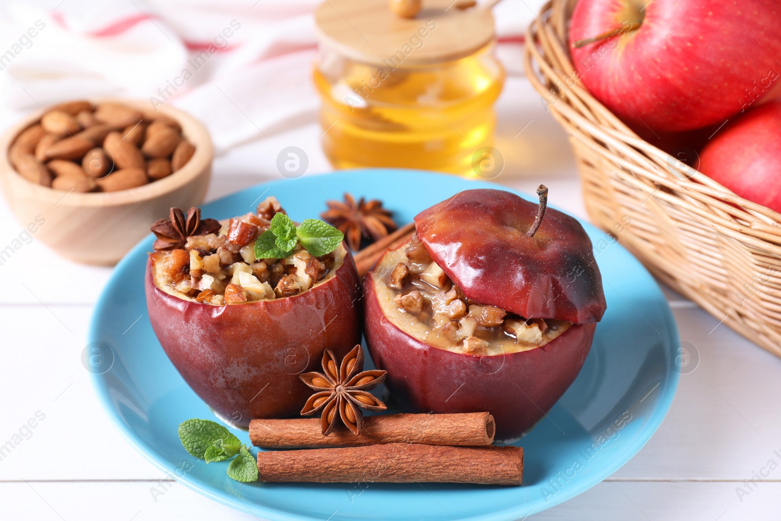 Photo of Tasty baked apples with nuts, honey, spices and mint on white wooden table, closeup