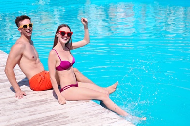 Photo of Happy young couple sitting near swimming pool
