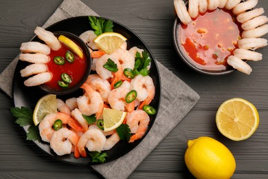 Photo of Tasty boiled shrimps with cocktail sauce, chili, parsley and lemon on grey wooden table, flat lay