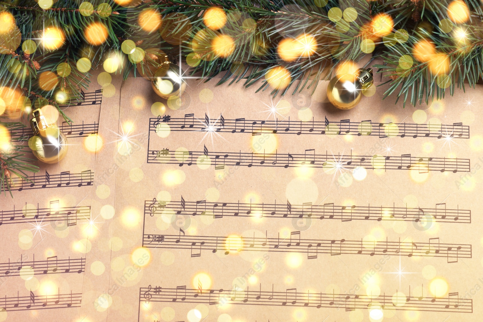 Image of Fir branches and golden balls on Christmas music sheets, above view. Bokeh effect