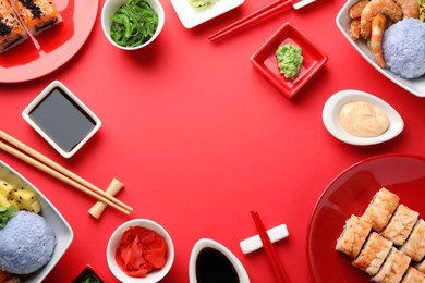 Frame made with delicious sushi rolls and poke bowls on red background, flat lay. Space for text