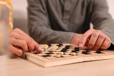 Photo of Couple playing checkers at wooden table, closeup