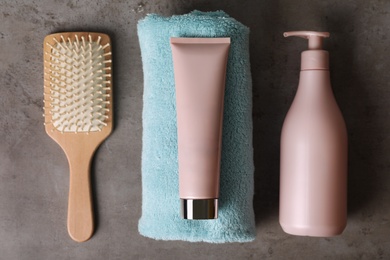 Photo of Different hair products, towel and brush on grey table, flat lay