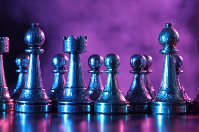 Photo of Chess pieces on checkerboard in color light