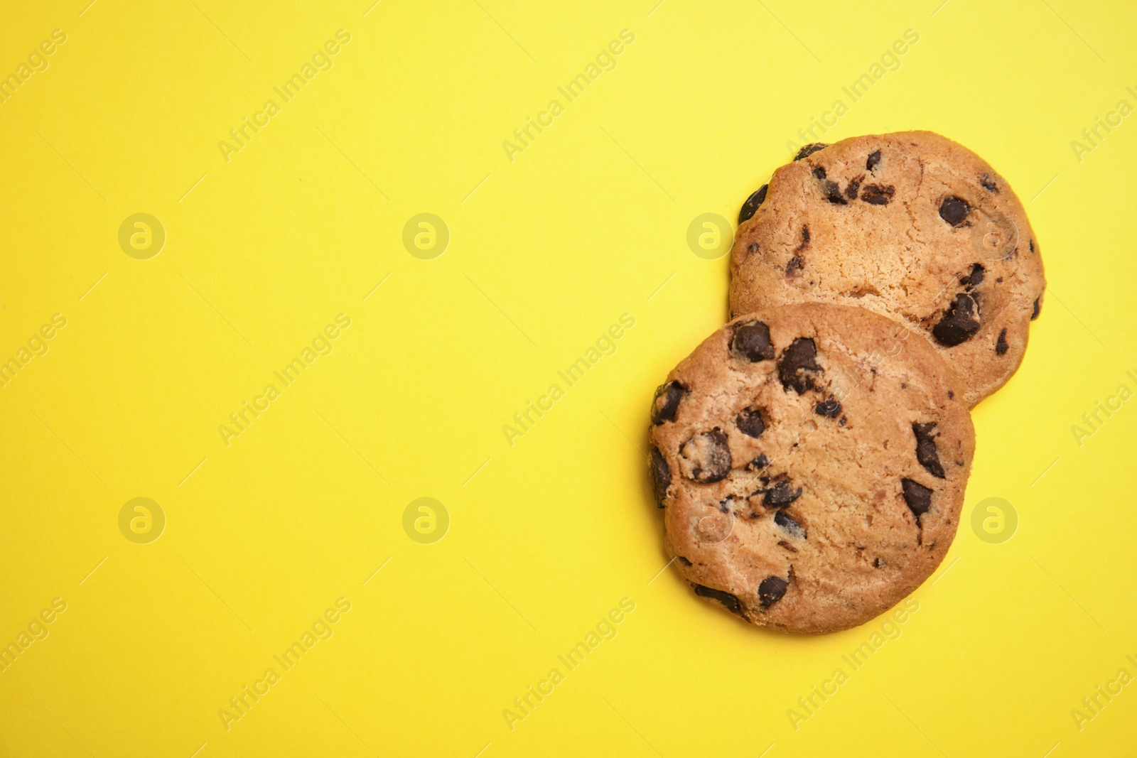 Photo of Delicious chocolate chip cookies on color background, flat lay. Space for text