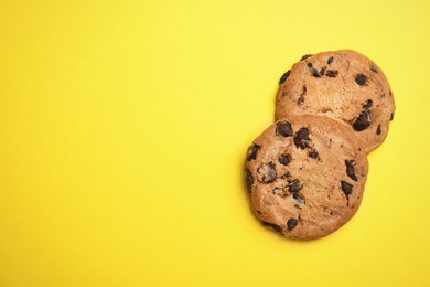 Photo of Delicious chocolate chip cookies on color background, flat lay. Space for text