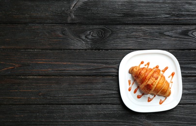 Photo of Plate of tasty croissant with jam and space for text on dark wooden background, top view. French pastry