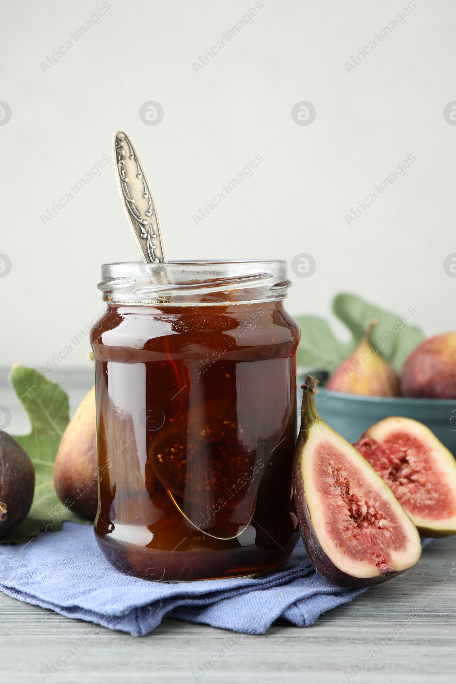 Photo of Jar of tasty sweet jam and fresh figs on grey table