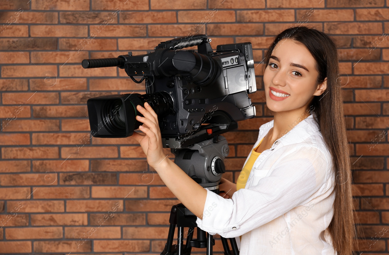 Photo of Operator with professional video camera near brick wall