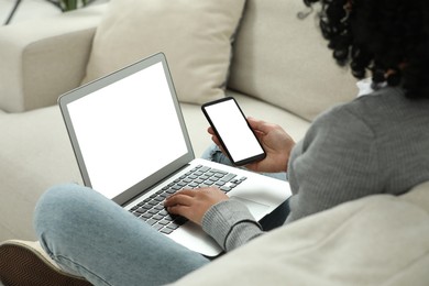 Photo of Woman using phone and laptop on sofa indoors, closeup. Space for text