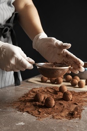 Woman preparing tasty chocolate truffles at table, closeup