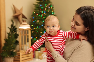 Happy young mother with her cute baby in room decorated for Christmas. Winter holiday