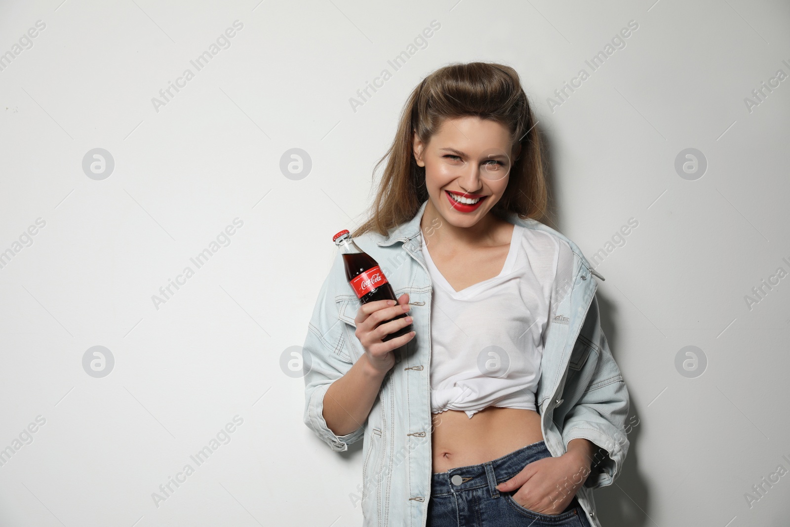 Photo of MYKOLAIV, UKRAINE - NOVEMBER 28, 2018: Young woman with bottle of Coca-Cola on white background