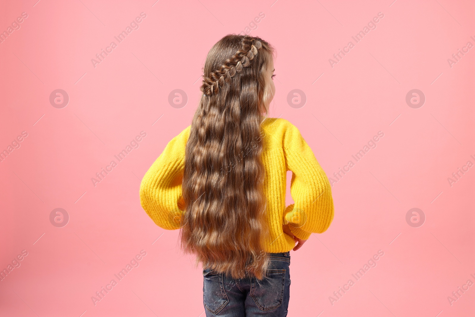 Photo of Little girl with braided hair on pink background, back view