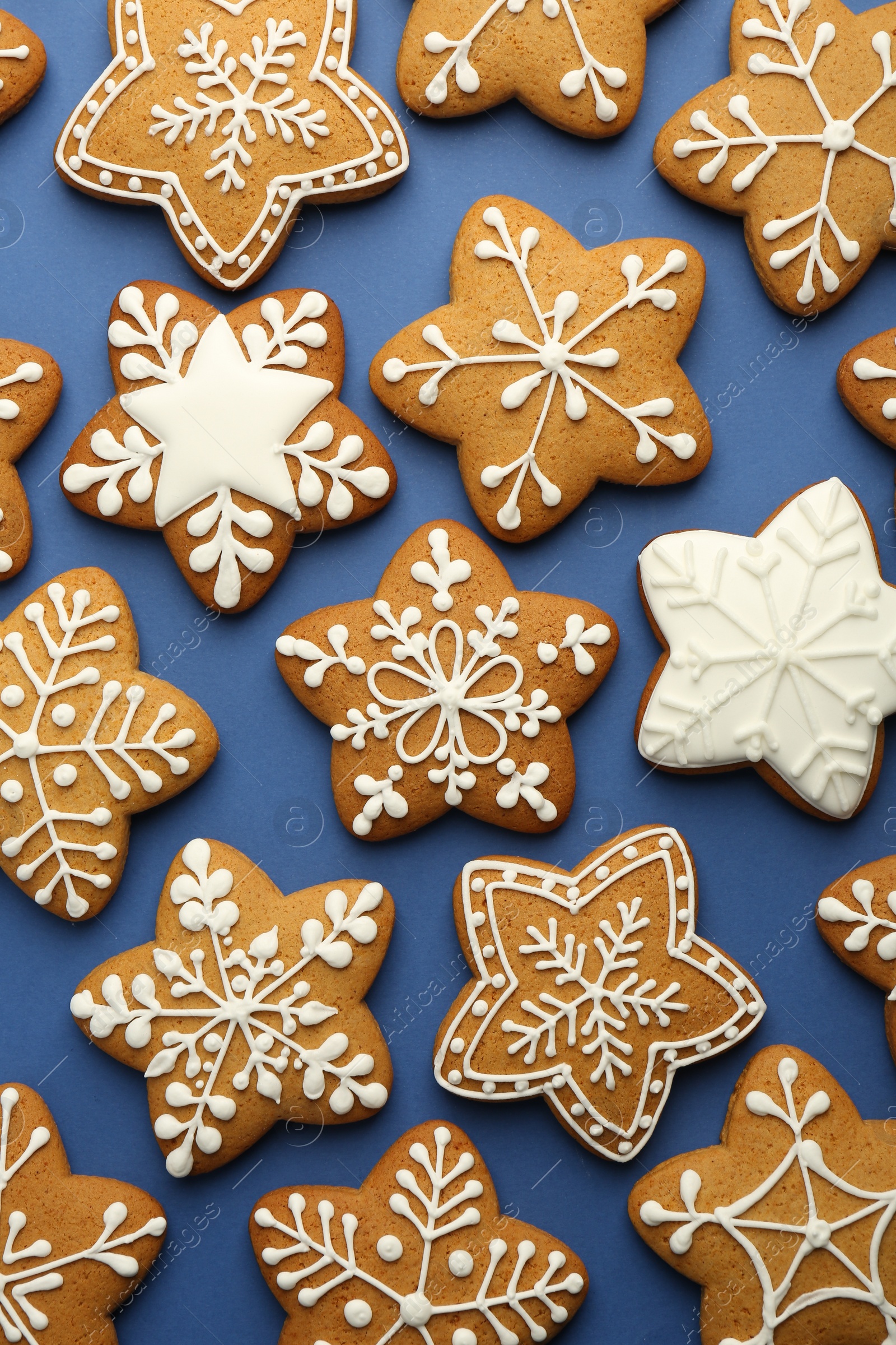 Photo of Tasty star shaped Christmas cookies with icing on blue background, flat lay