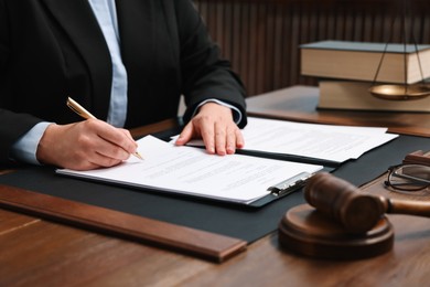 Photo of Lawyer working with documents at wooden table indoors, closeup