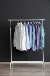 Wardrobe rack with men's clothes near dark wall