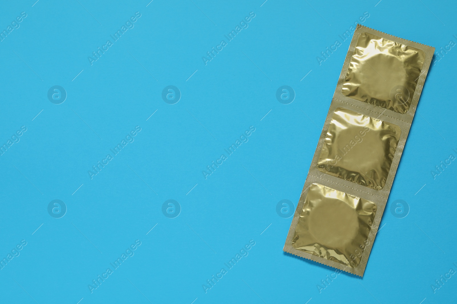 Photo of Condom packages on light blue background, top view and space for text. Safe sex