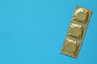 Photo of Condom packages on light blue background, top view and space for text. Safe sex