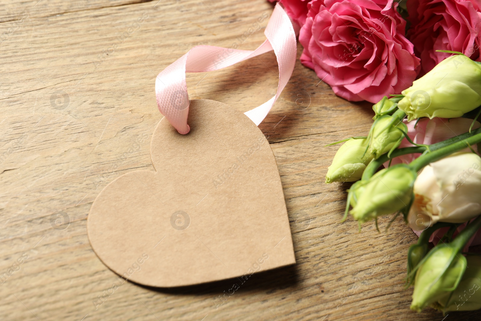 Photo of Happy Mother's Day. Beautiful flowers with blank heart shaped card on wooden table, closeup