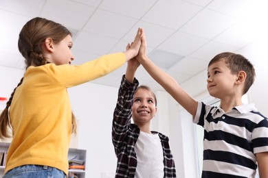 Photo of Happy children giving high five at school, low angle view