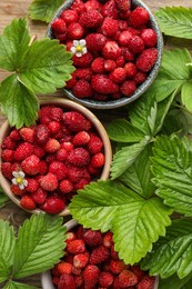 Photo of Fresh wild strawberries in bowls and leaves on table, flat lay