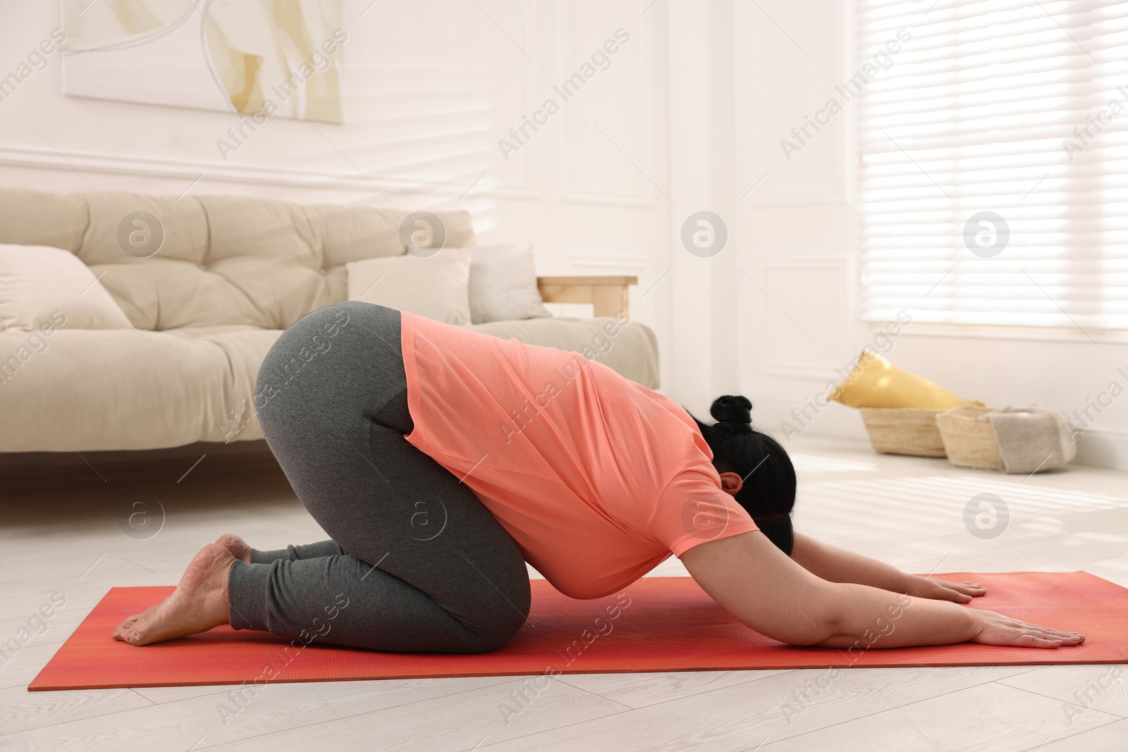 Photo of Overweight mature woman doing exercise on yoga mat at home