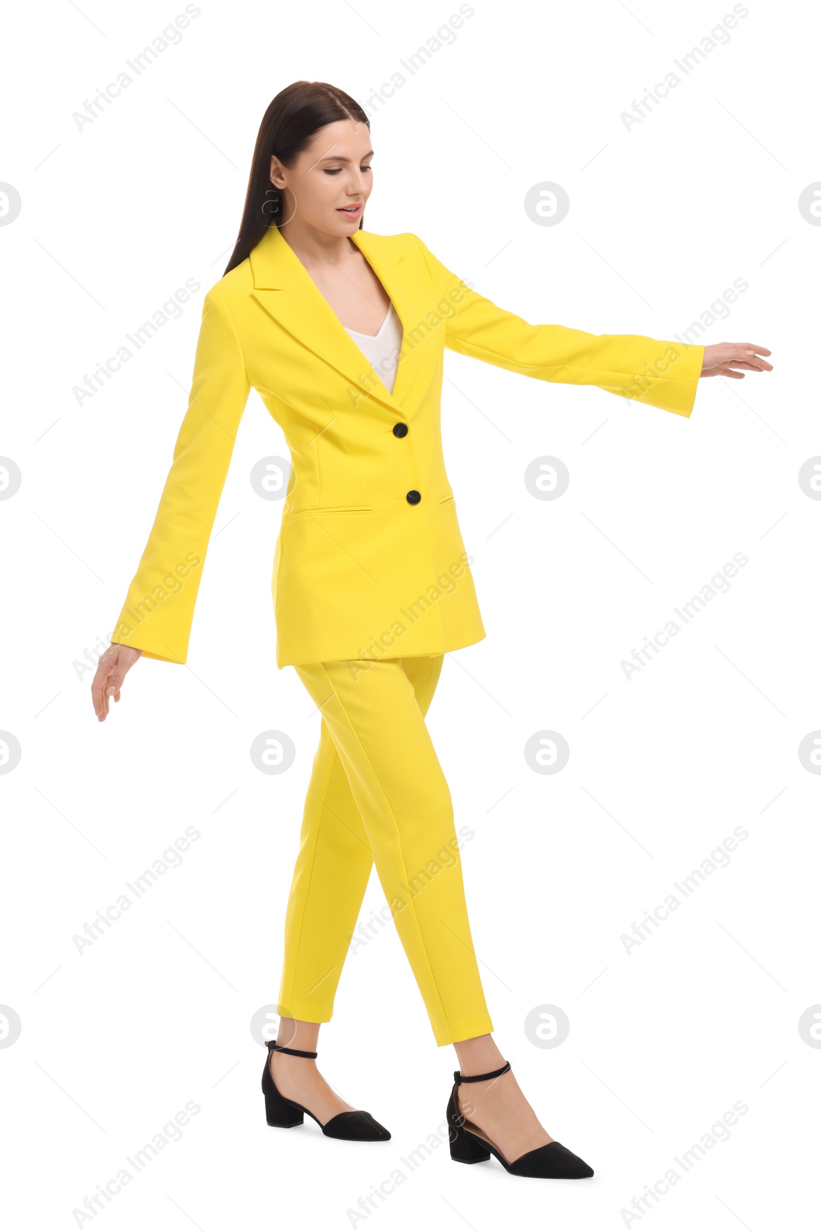 Photo of Beautiful businesswoman in yellow suit walking on white background