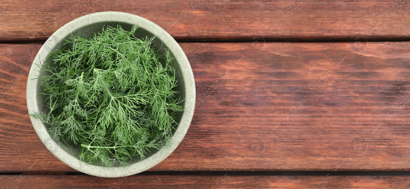 Image of Fresh dill in bowl on wooden table, top view. Banner design with space for text