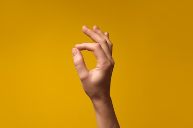 Woman holding something in hand on yellow background, closeup. Space for text