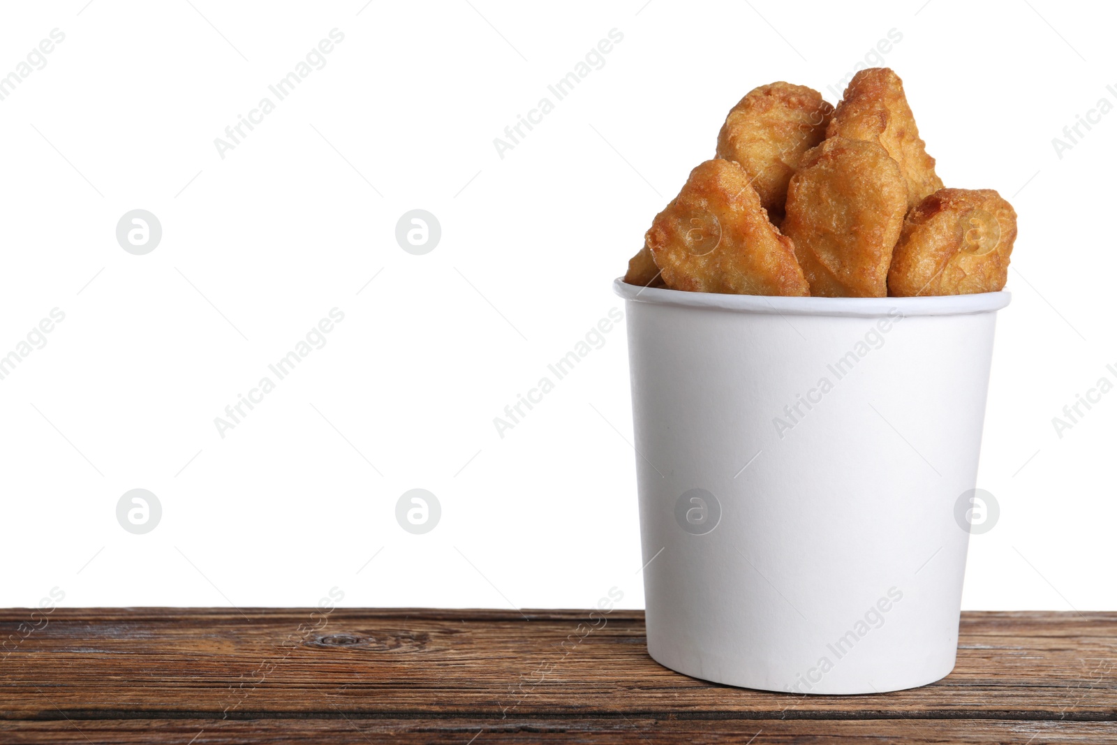 Photo of Bucket with tasty chicken nuggets on wooden table against white background. Space for text