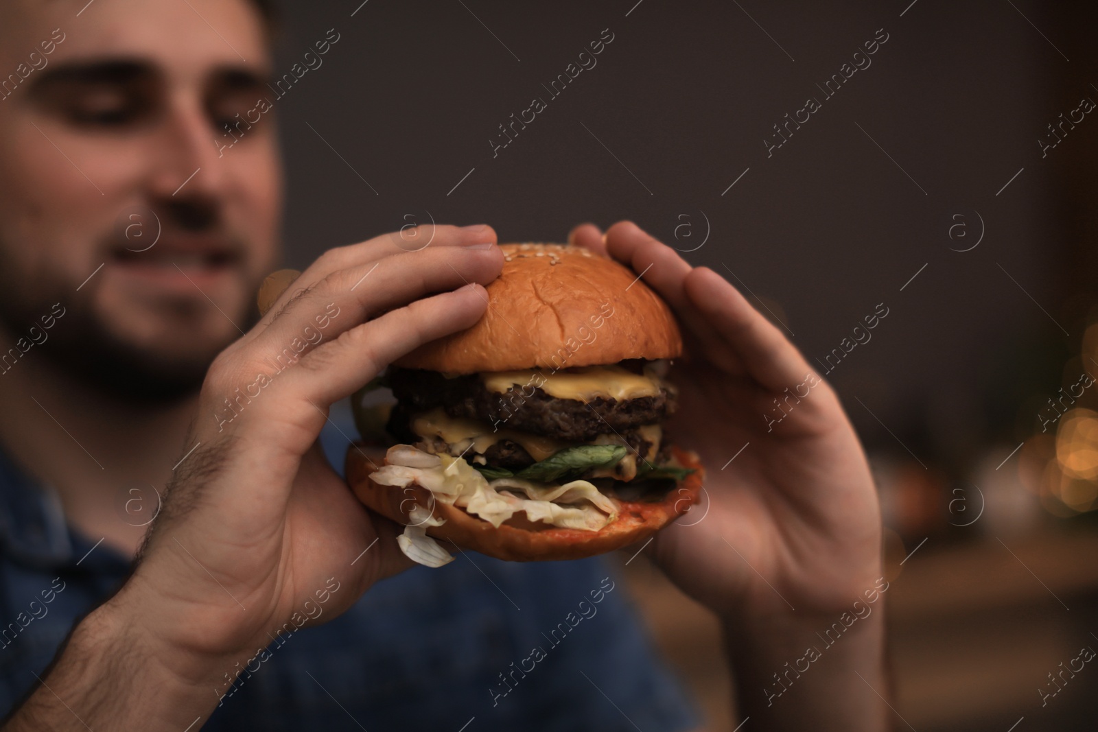 Photo of Young man eating tasty burger in cafe