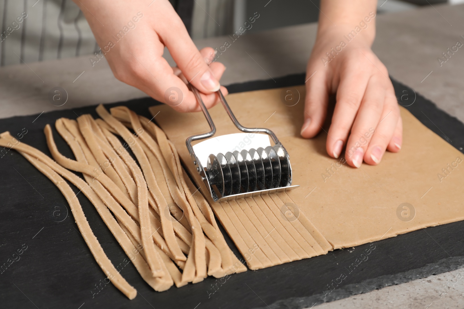 Photo of Woman cutting dough for soba at table, closeup