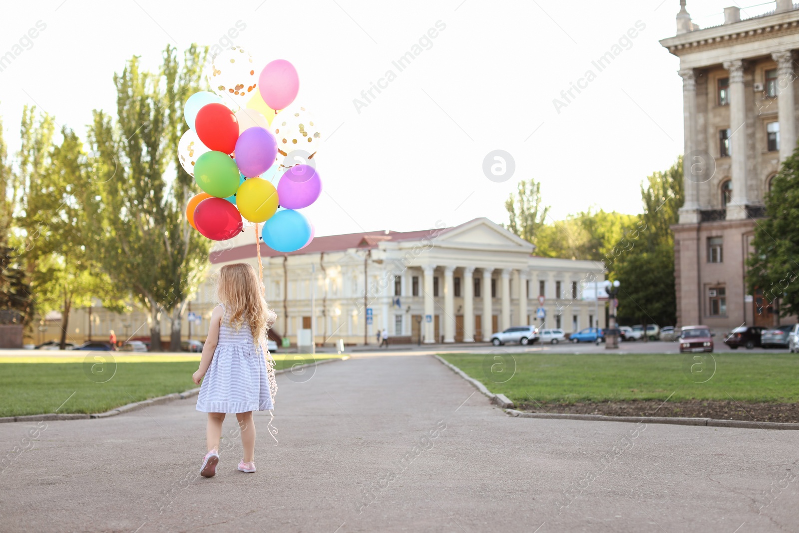 Photo of Cute little girl with colorful balloons outdoors on sunny day